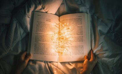 person holding string lights on opened book